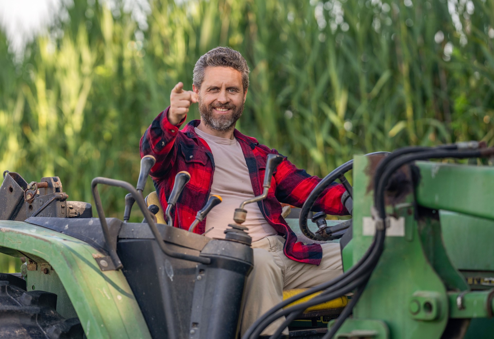 Crop harvesting. Agriculture equipment. Farmer with harvesting machinery. Mature man at tractor. Tractor driver. Agriculture and field work. Farmer in field with tractor outdoor. Point finger