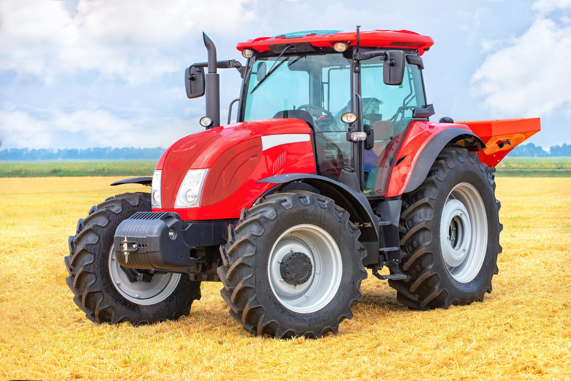 Powerful red tractor in vast wheat field under blue sky, showcasing modern agricultural machinery concept